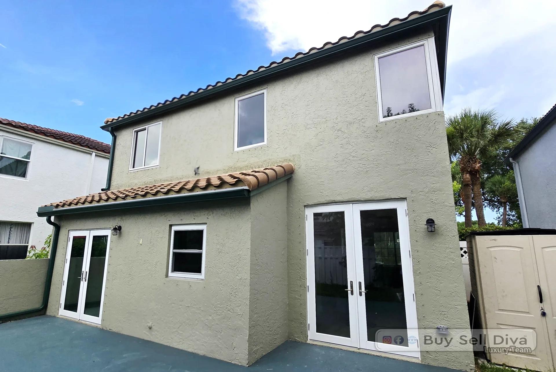 Rear patio of the Coral Springs home showing white impact-rated french doors and windows below a barrel tile roof