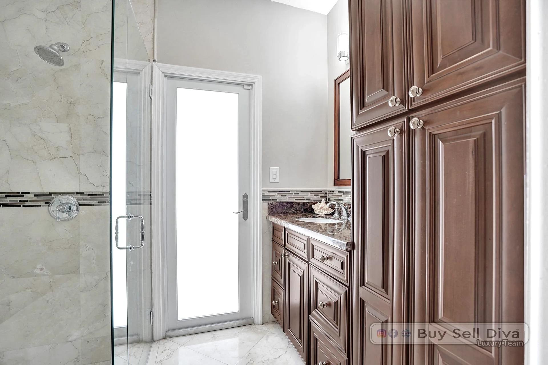 Bathroom with rich wood cabinetry and glass shower in a Weston Florida home.