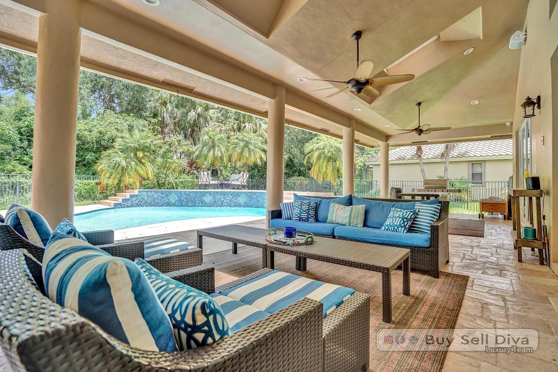 Covered lanai with outdoor lounge seating overlooking the pool