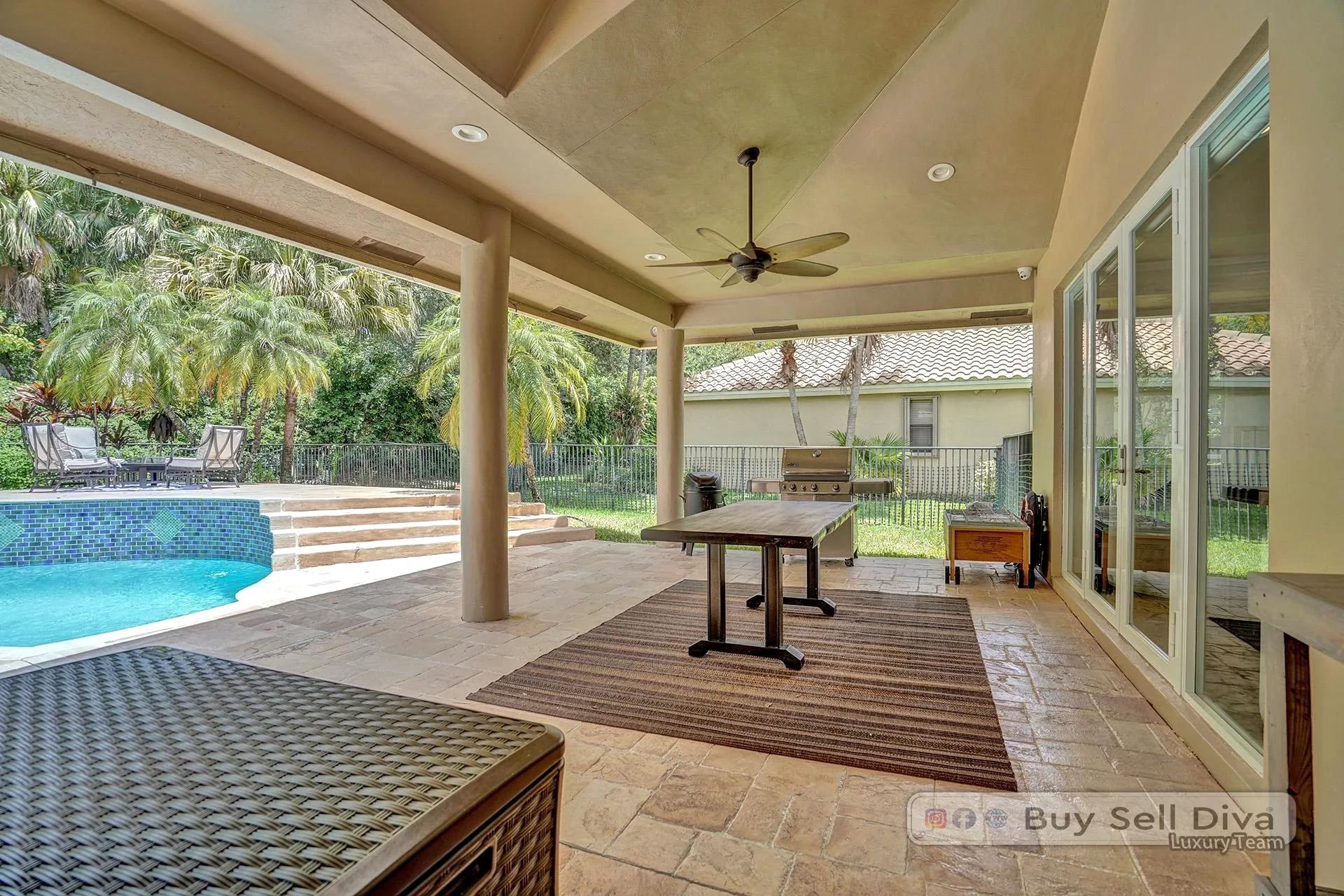 Covered patio with travertine pavers and pool view at a Weston Florida home.
