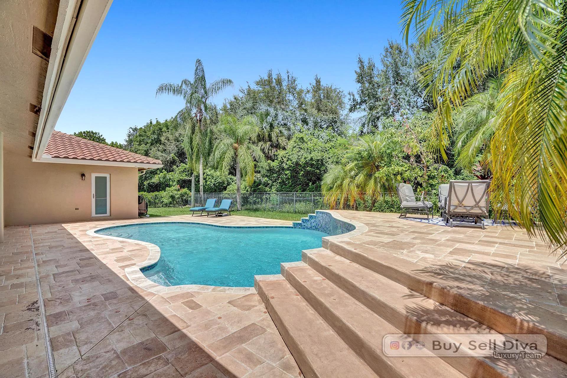 Freeform pool with travertine deck and tropical landscaping in Weston Florida.