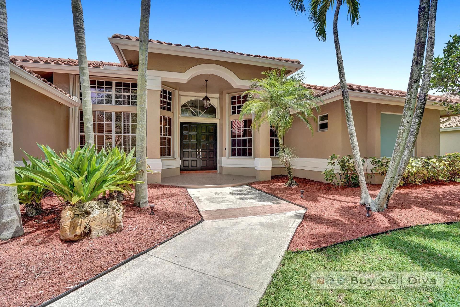 Front walkway lined with palms leading to the covered entry of a Weston Florida home.