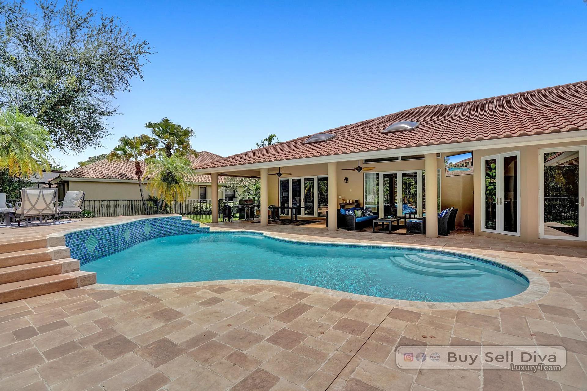 Oversized freeform pool with steps and travertine deck in the backyard of 1260 Manor Court in Weston Florida