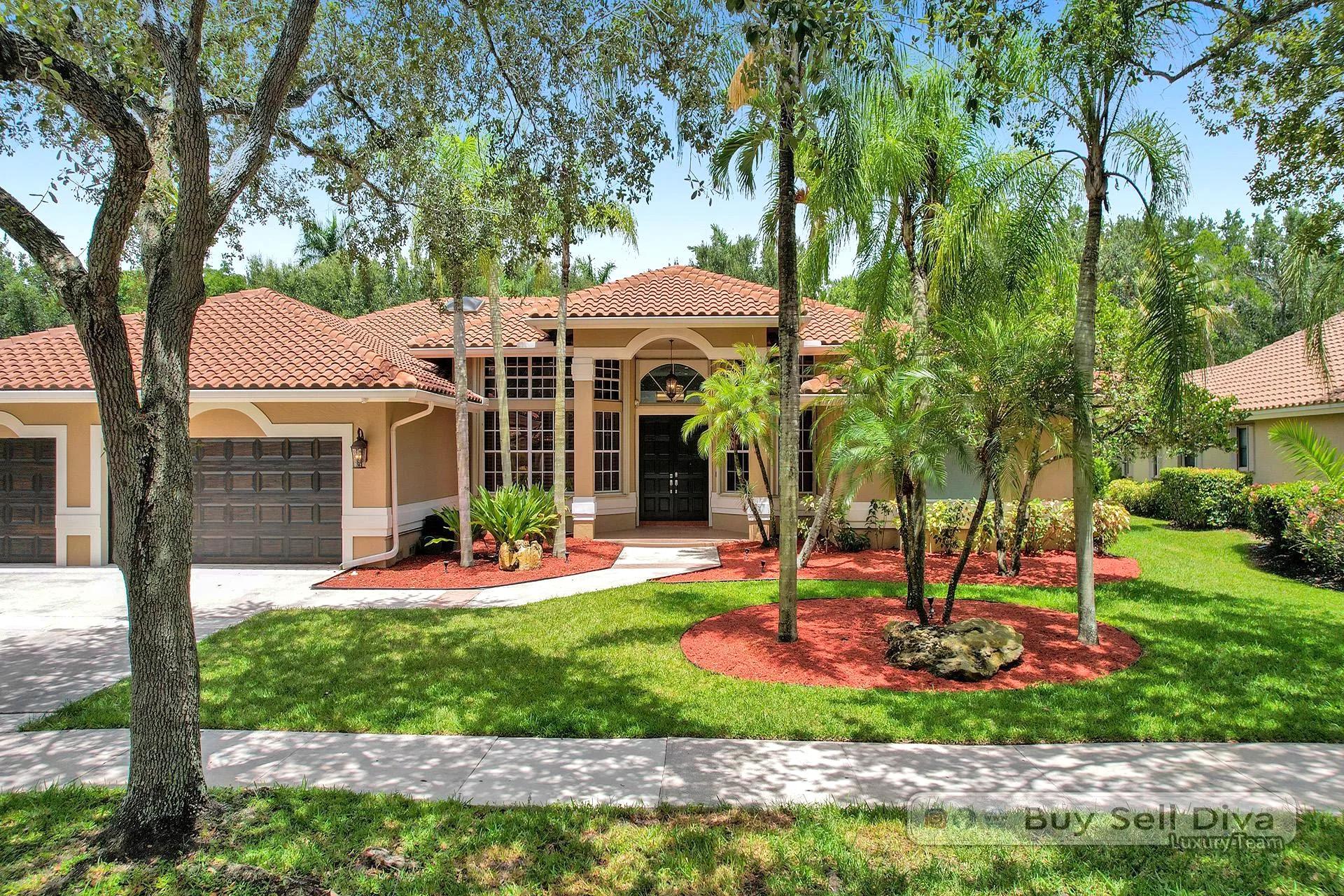 Front exterior of 1260 Manor Court, a single-story pool estate with barrel tile roof under a mature oak in Weston Florida
