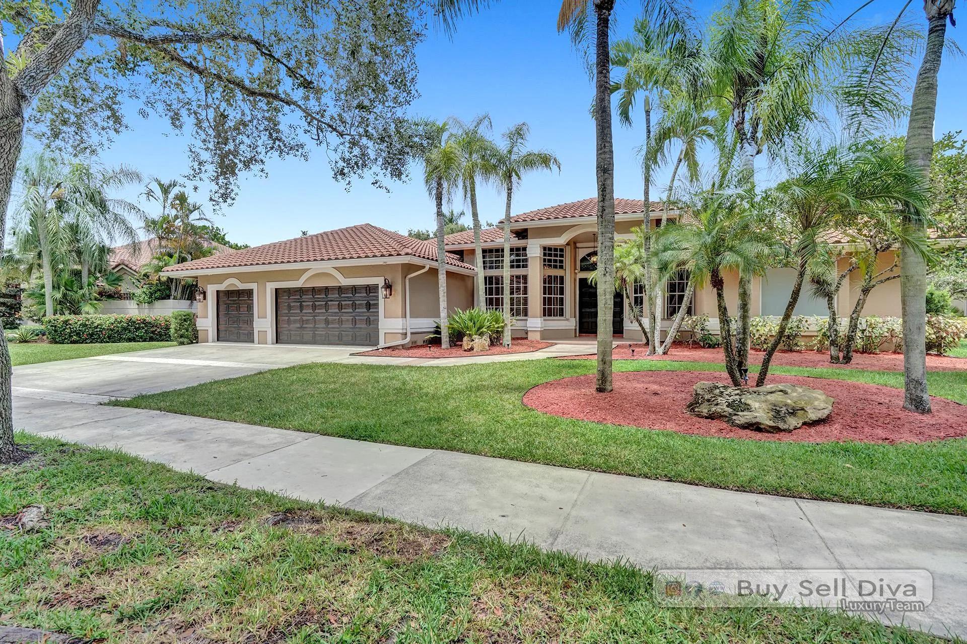 Front yard with palms and tropical landscaping at a single-story Weston Florida pool home.