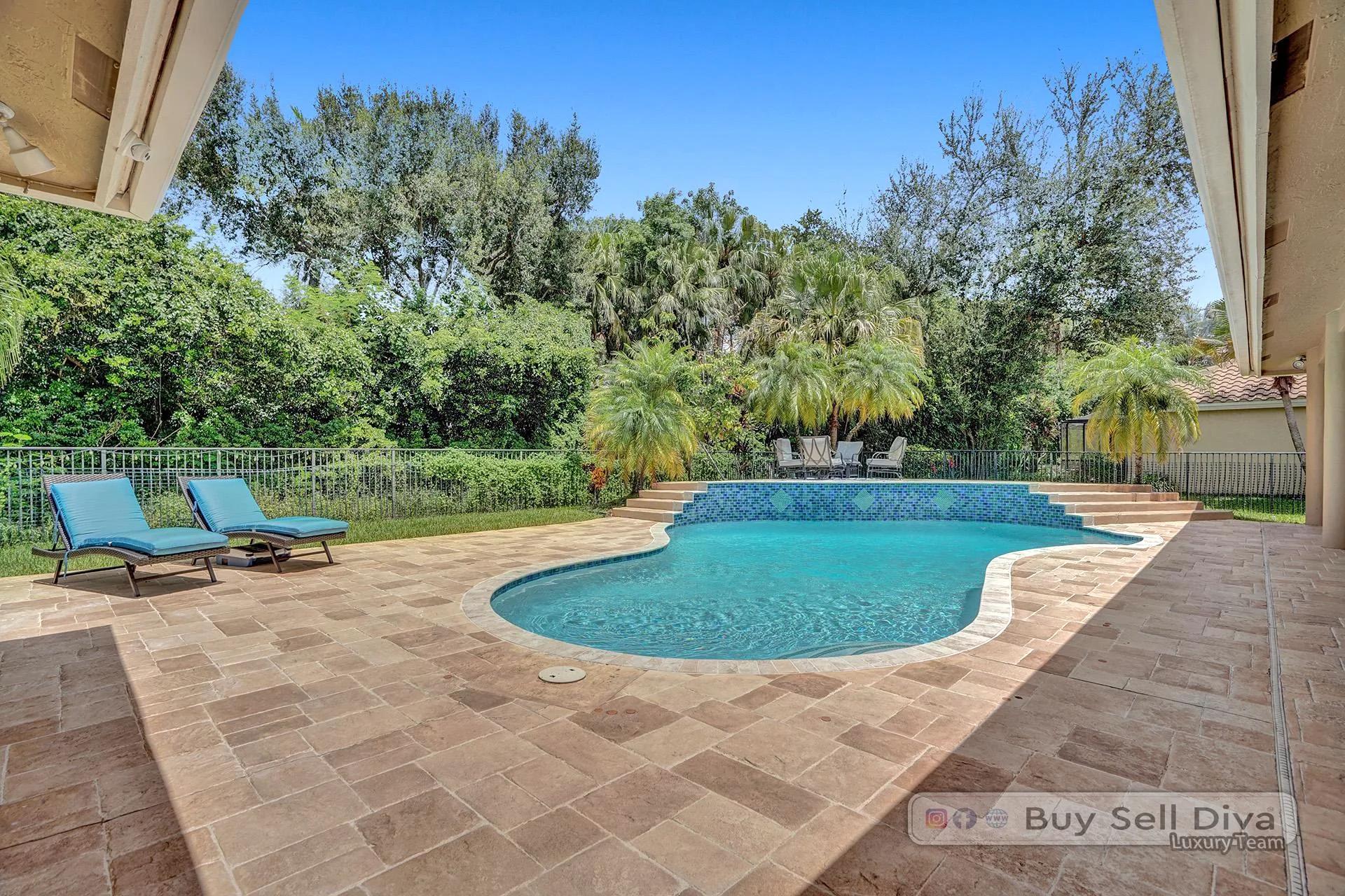 Pool loungers on a travertine patio beside a freeform pool in Weston Florida.