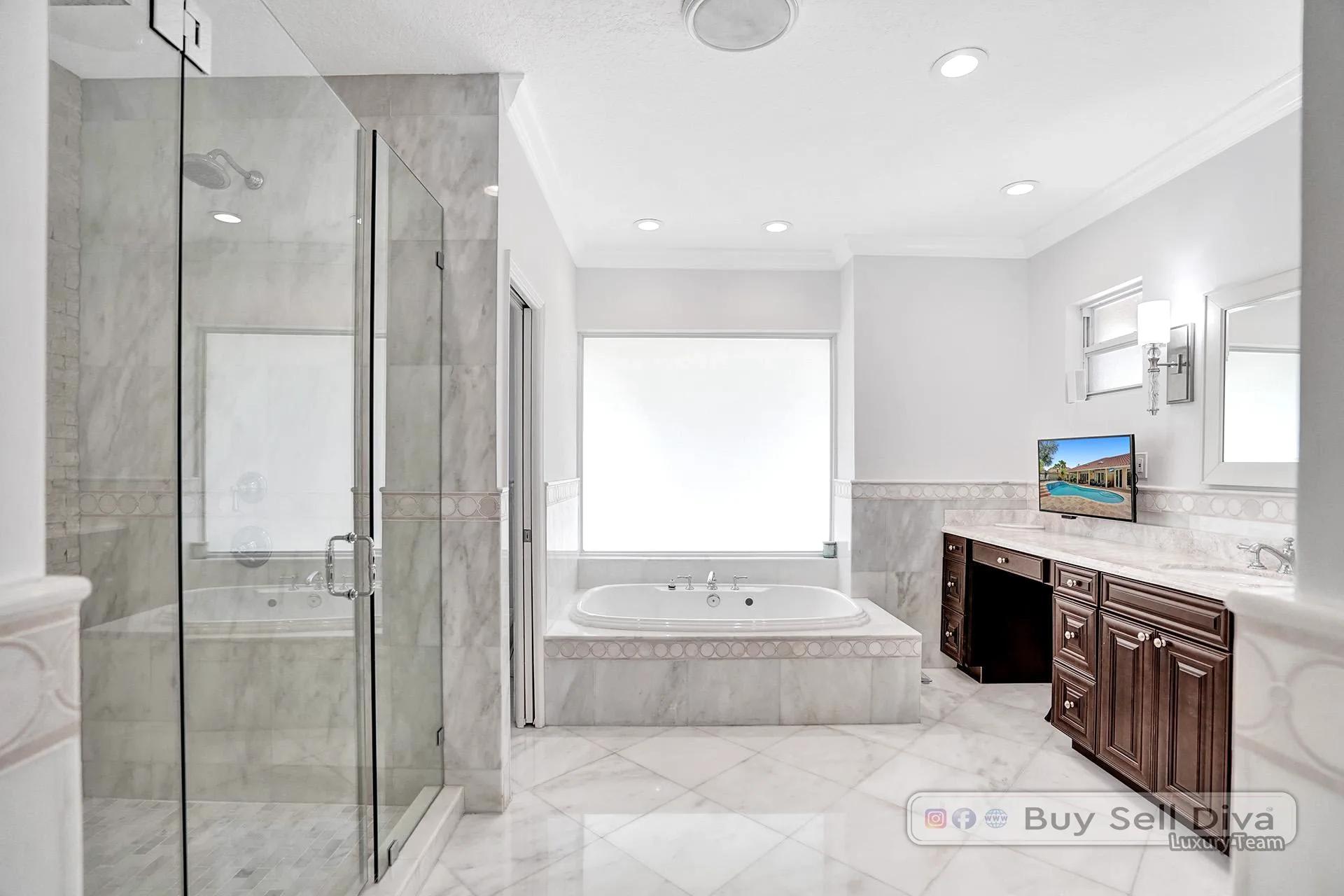 Remodeled primary bathroom with soaking tub, marble surround, and glass shower