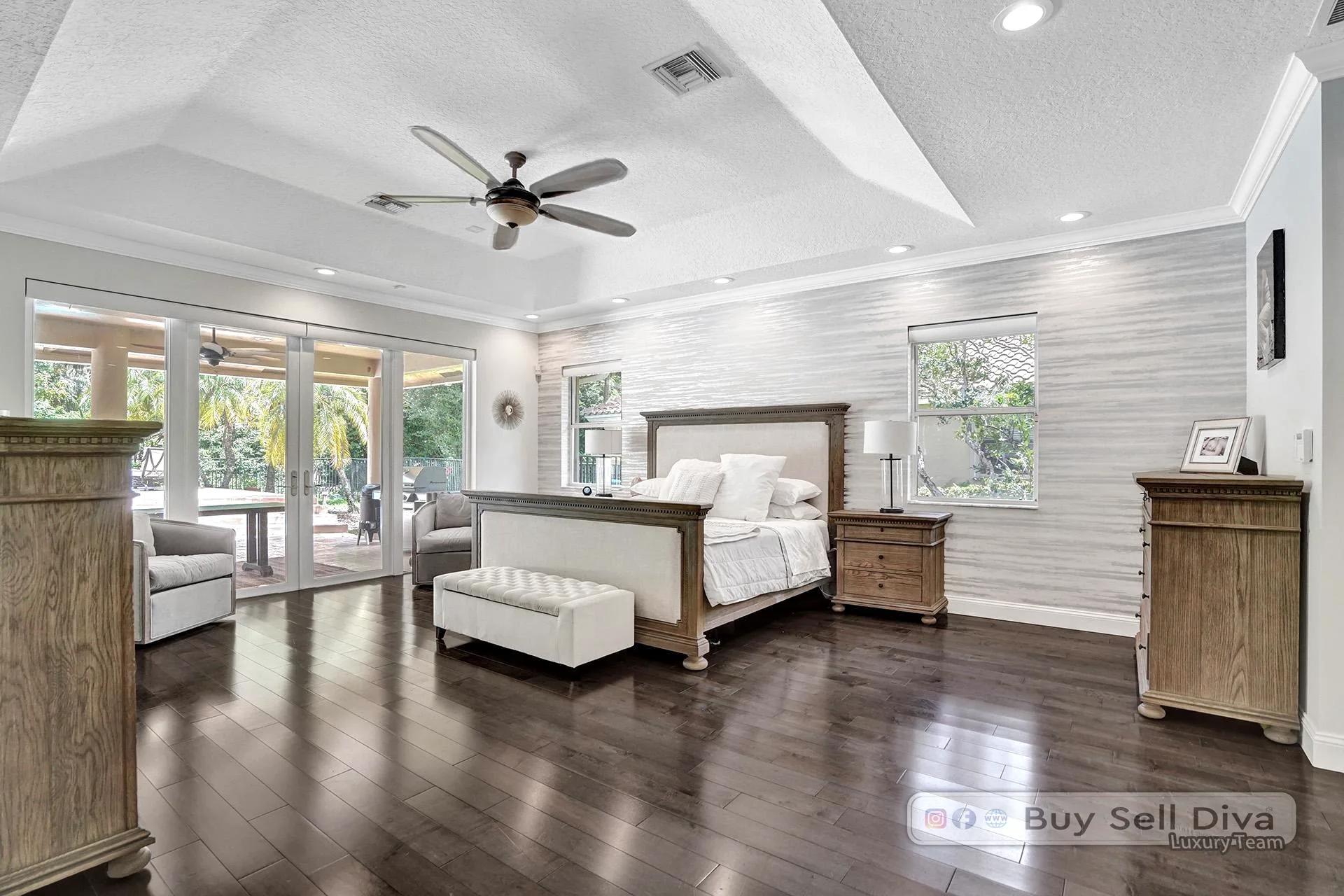 Primary bedroom suite with sitting area and wood floors in a Weston Florida home.