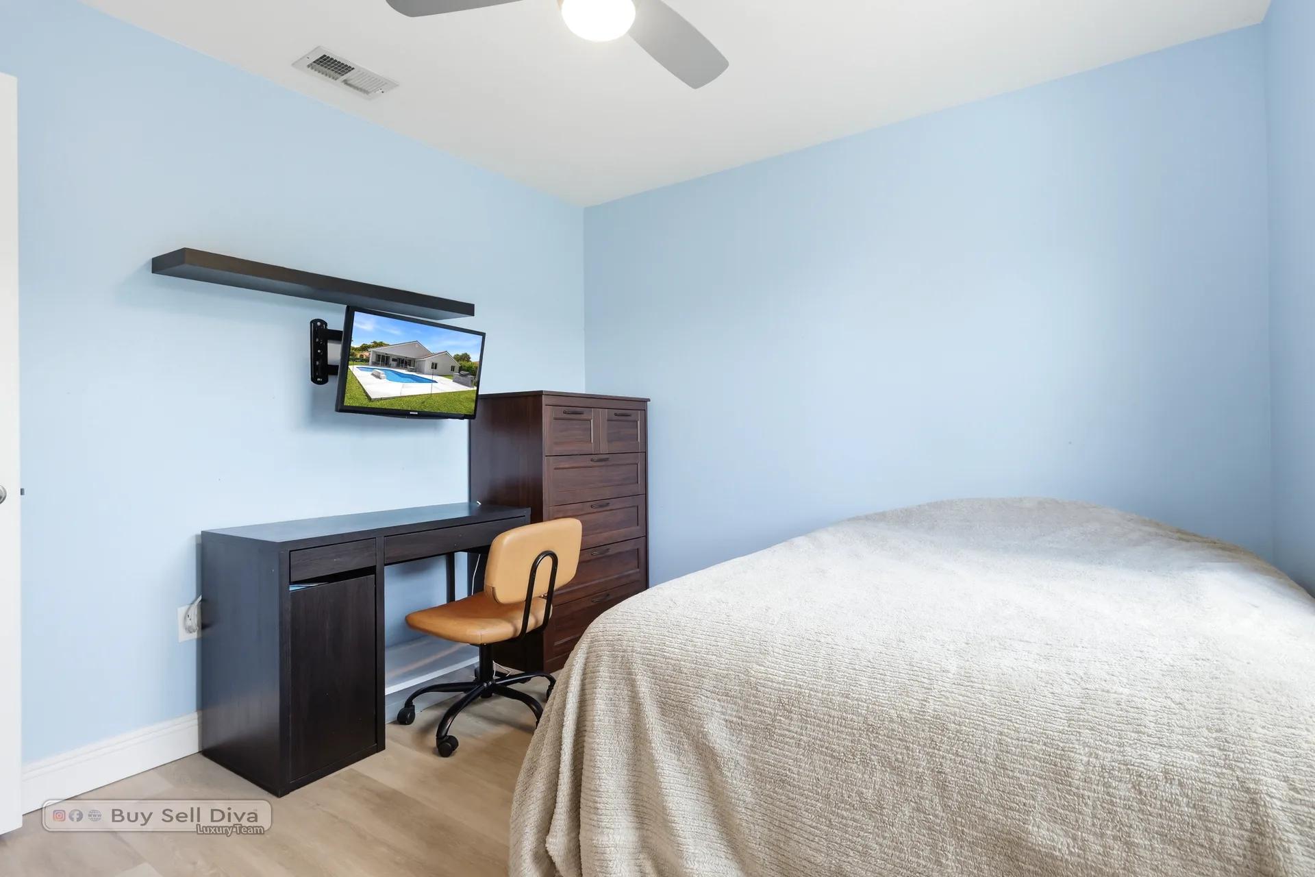 Secondary bedroom with built-in desk and mounted TV