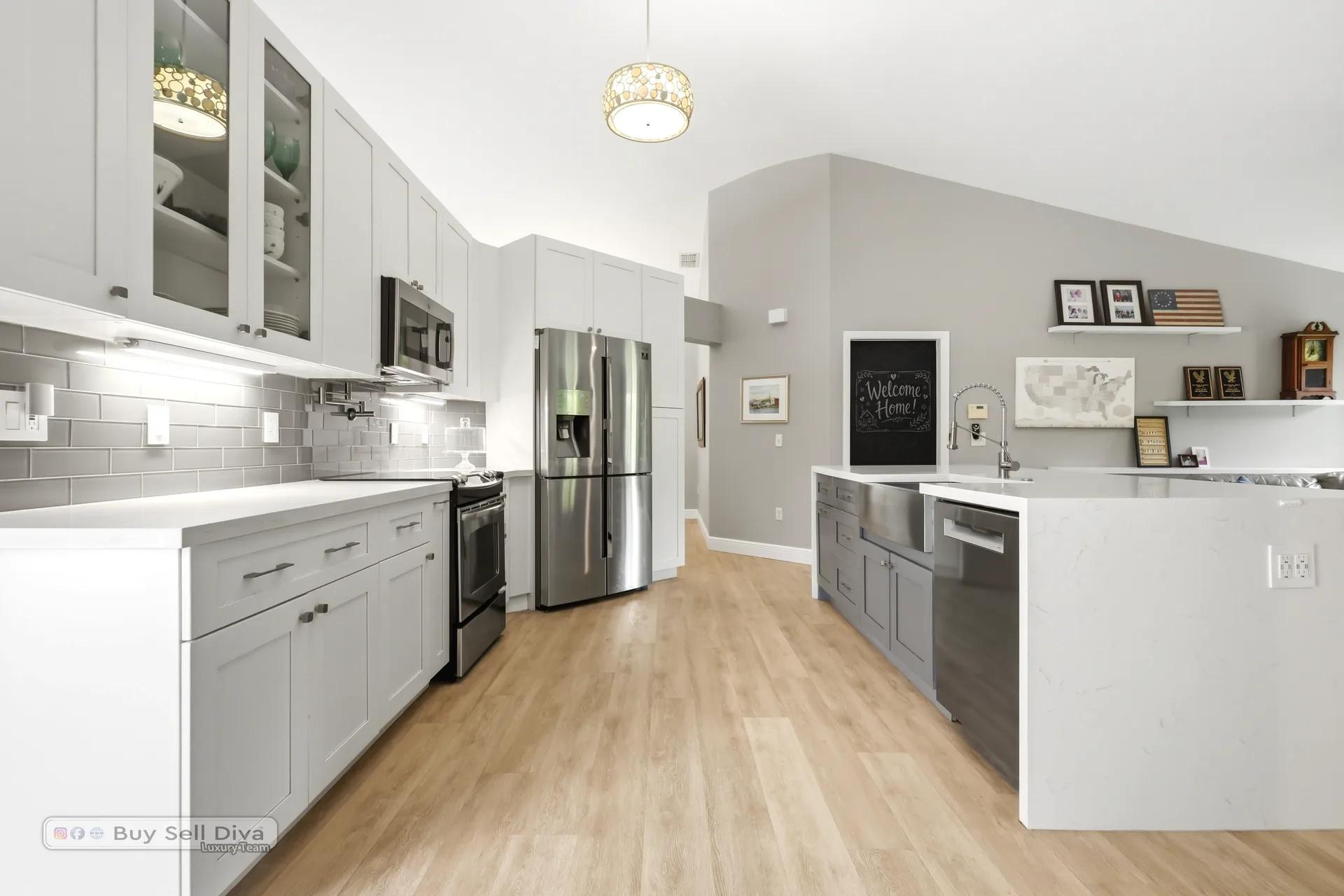 Galley view of the remodeled kitchen with glass-front cabinets and stainless appliances