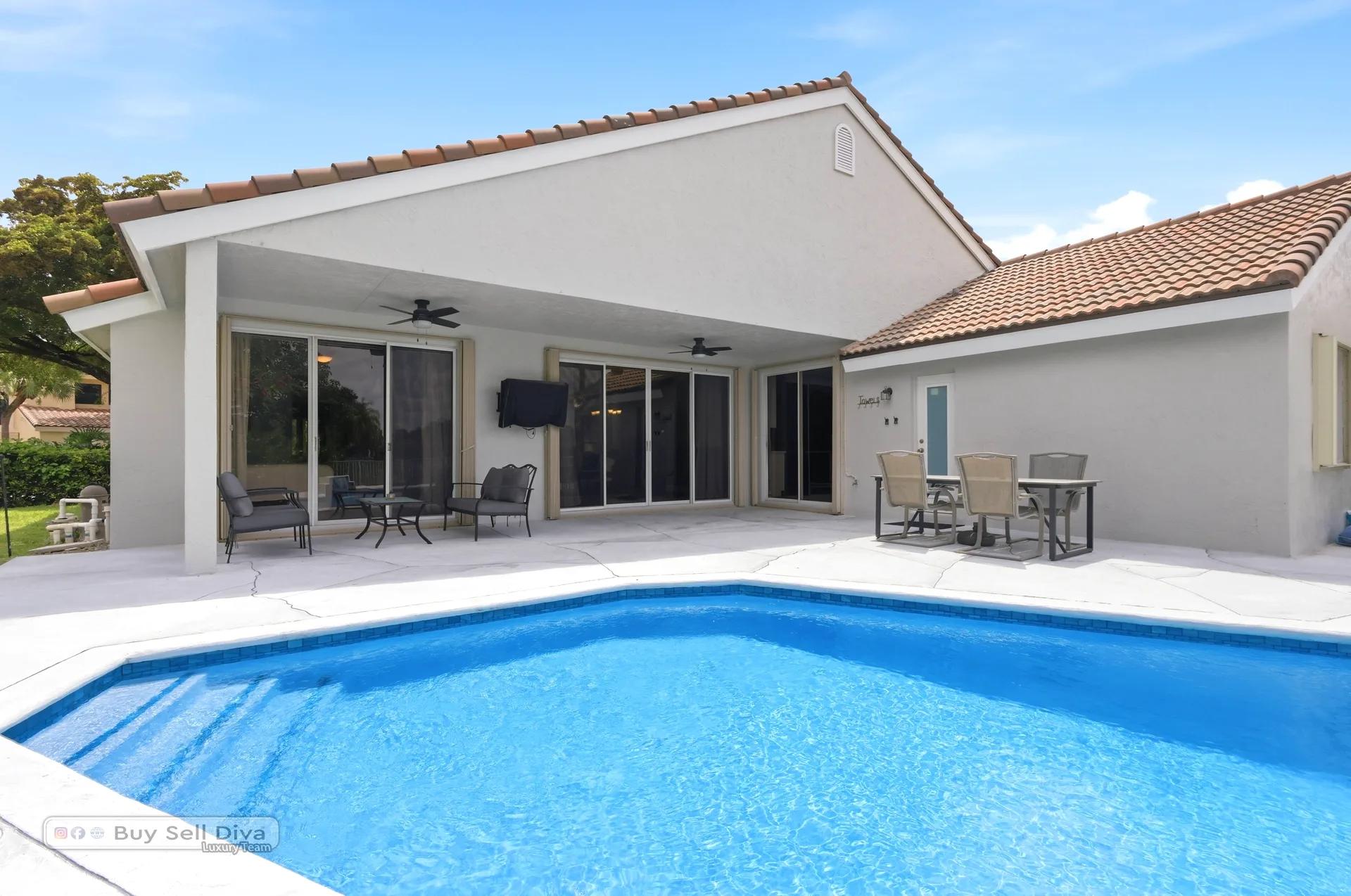 Back of the home with covered patio, ceiling fans, and pool