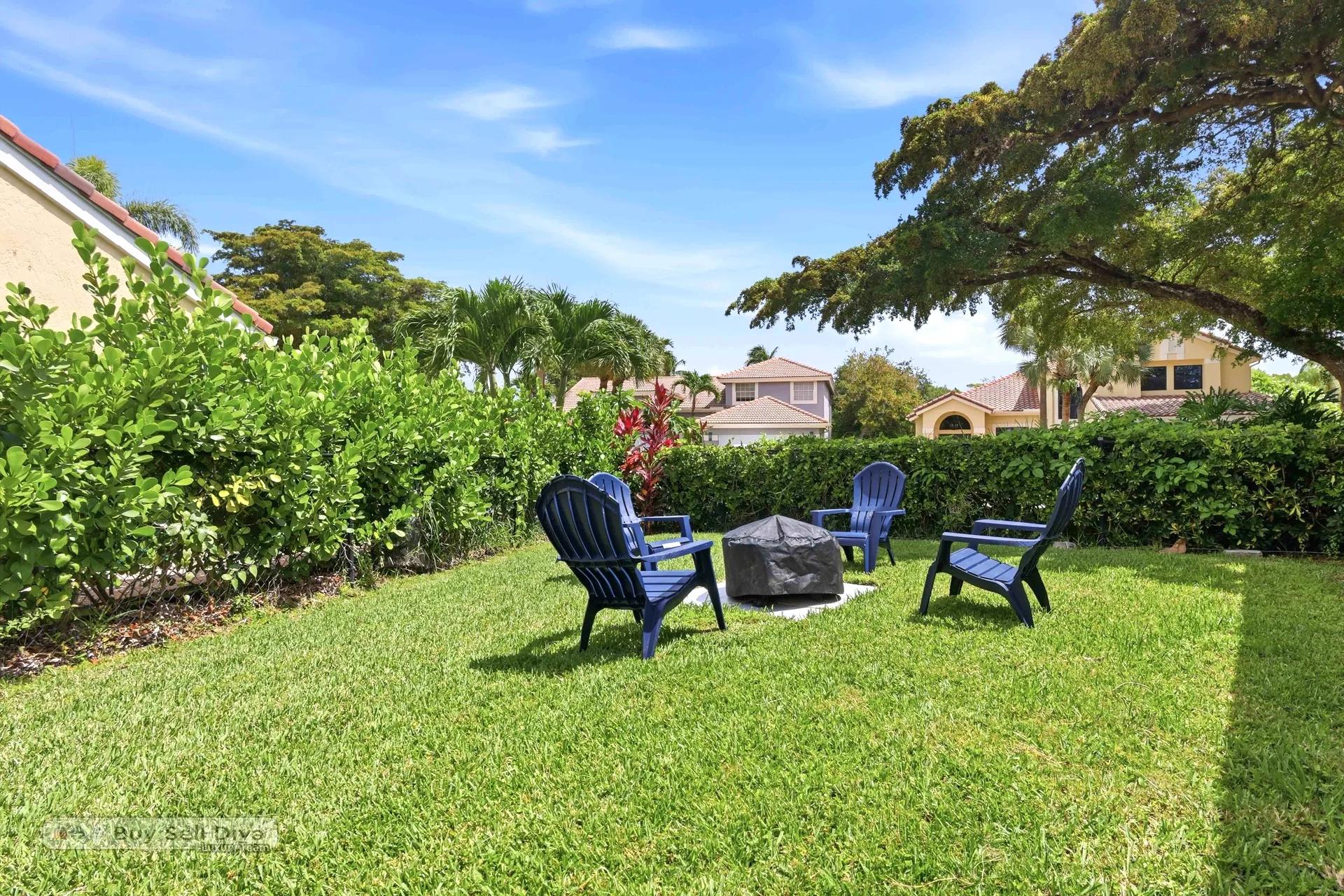 Grassy side yard with fire pit seating area and privacy hedge