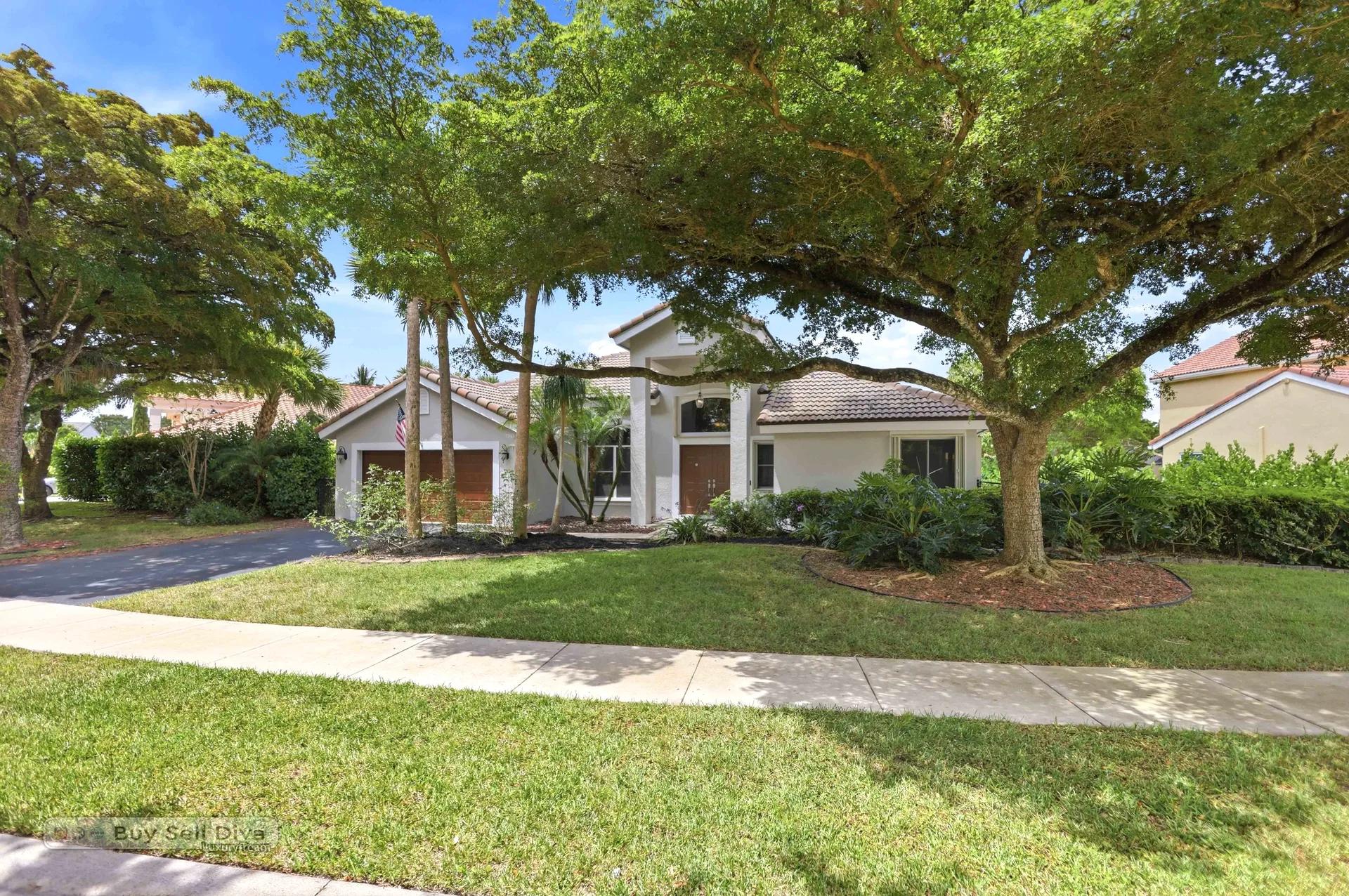 Curb view of the home framed by mature trees and tropical landscaping
