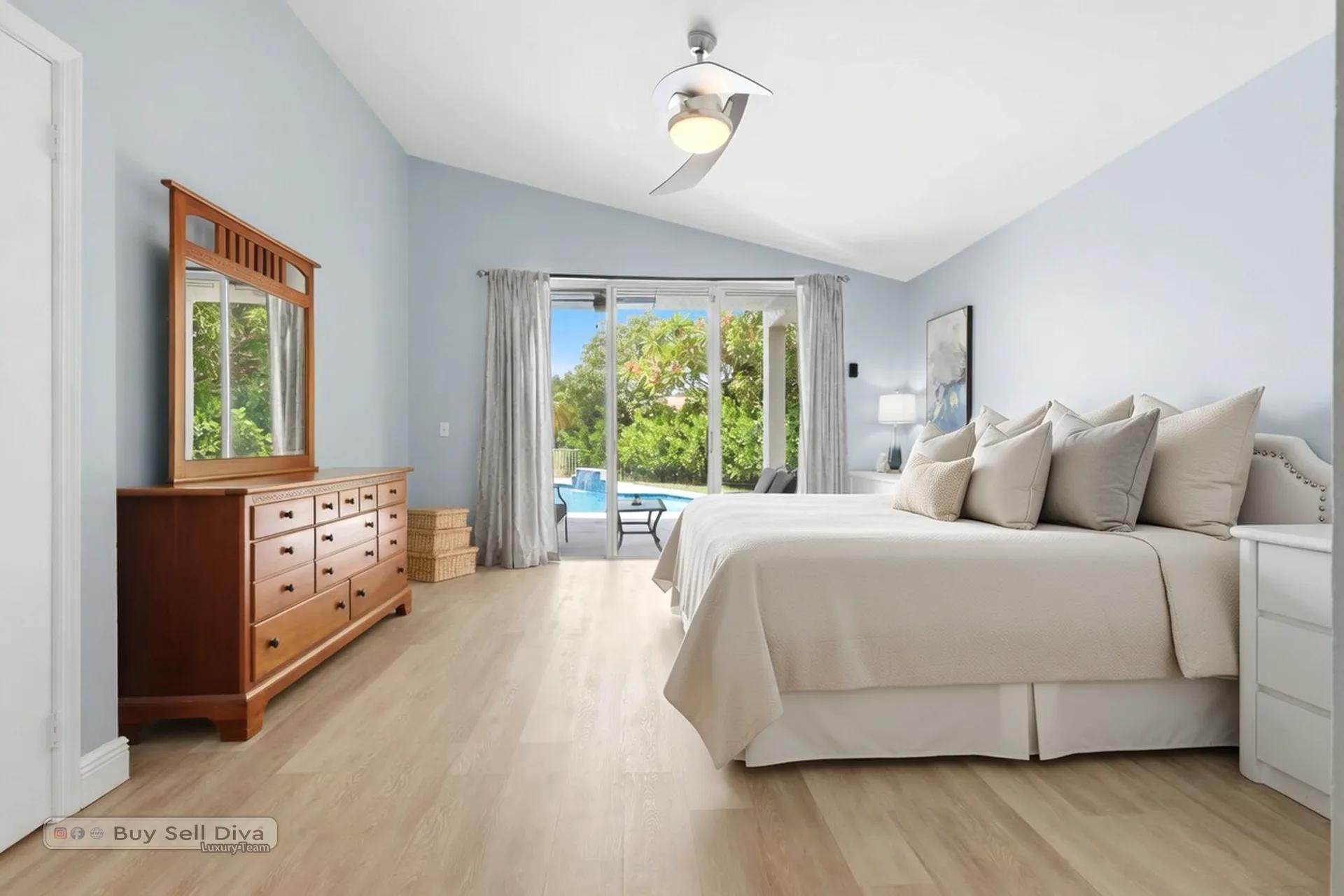 Primary bedroom with vaulted ceiling and slider access to the pool deck