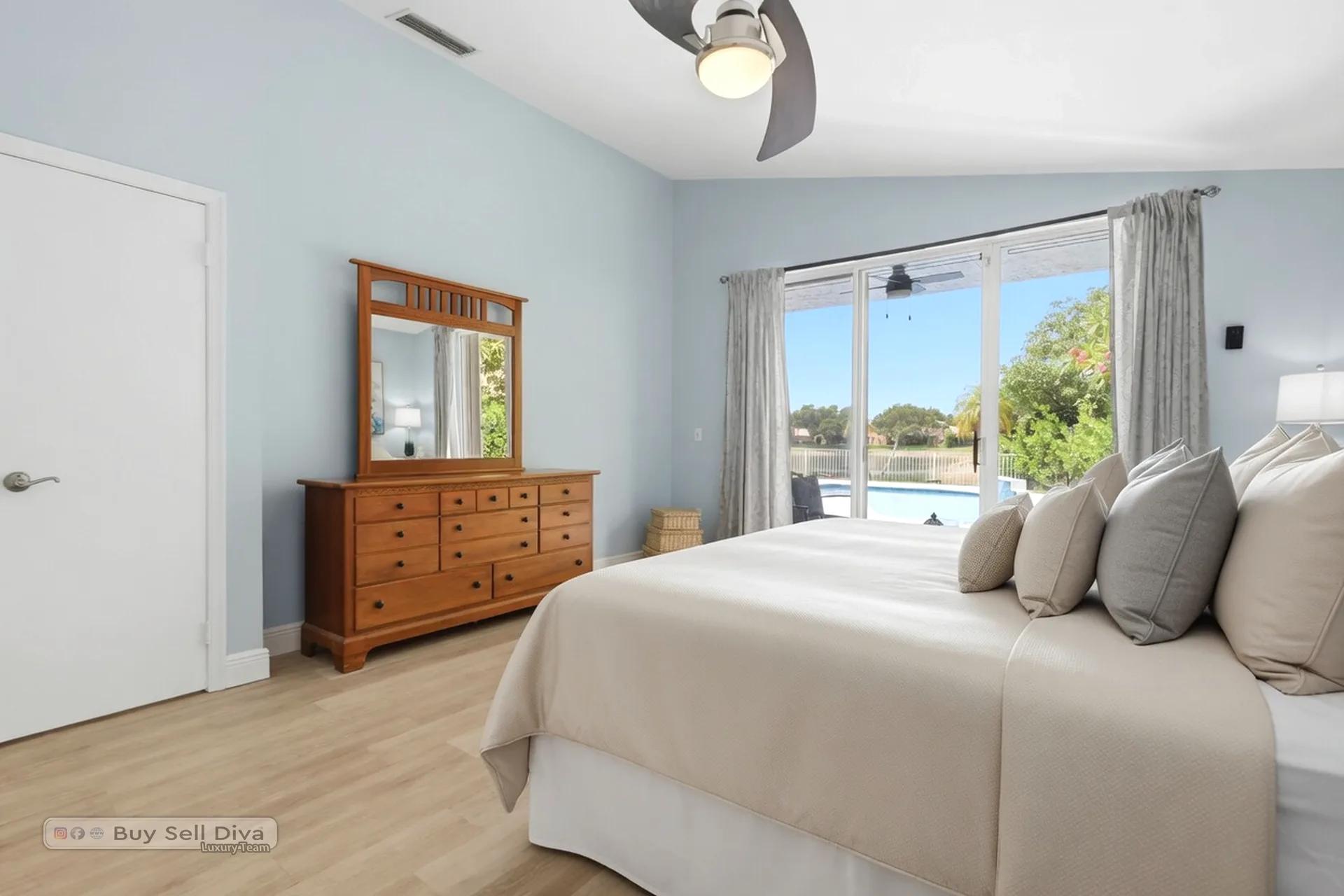 Primary bedroom with dresser and slider overlooking the pool