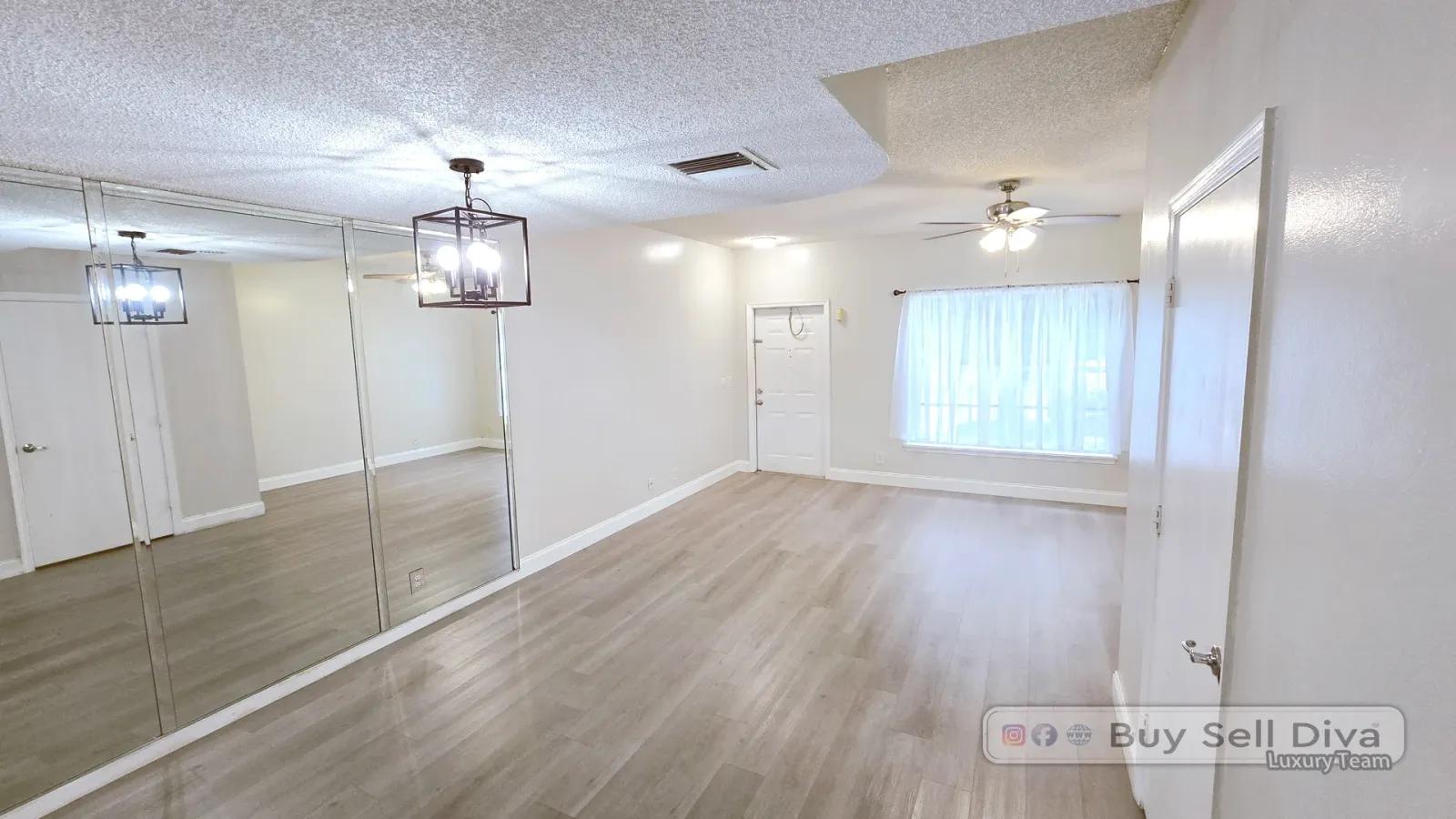 Coral Reef Club townhome living room with mirrored accent wall and new vinyl plank floors