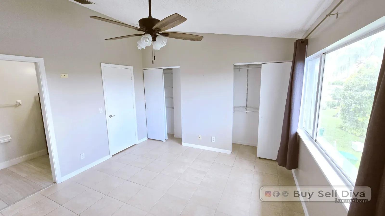 Primary bedroom with vaulted ceiling, two closets, and a lake view window in the Coral Springs townhome