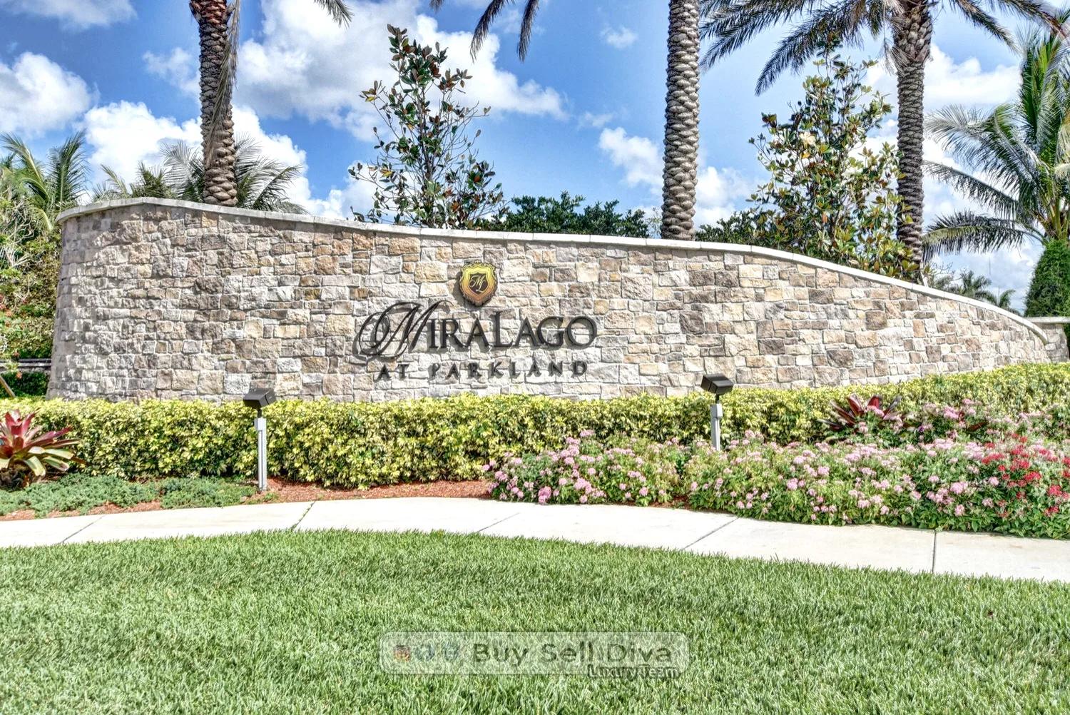 Stone entrance sign at MiraLago at Parkland Florida surrounded by palms and flowers
