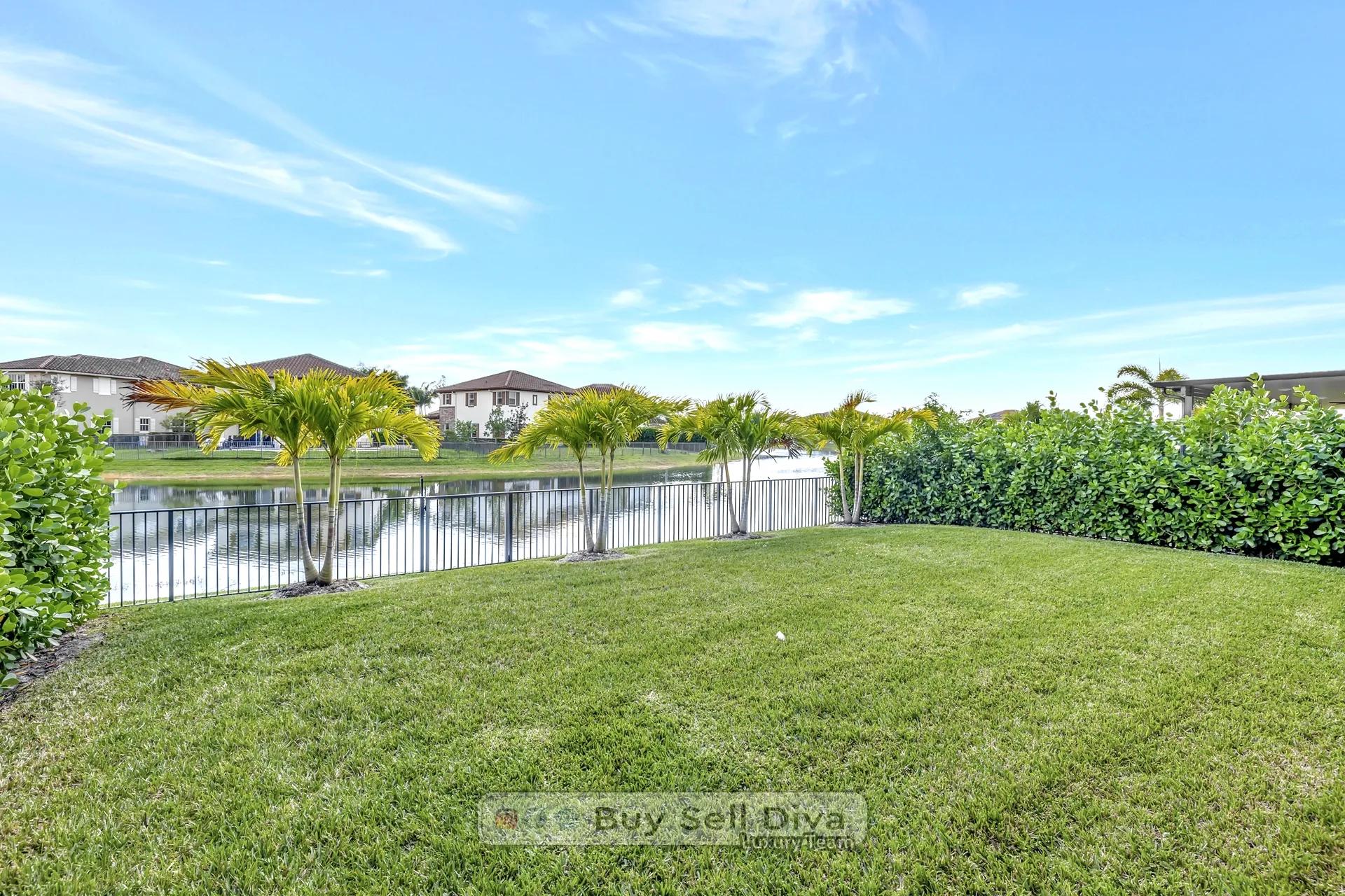 Fenced backyard with palm trees overlooking the lake behind the MiraLago home in Parkland Florida