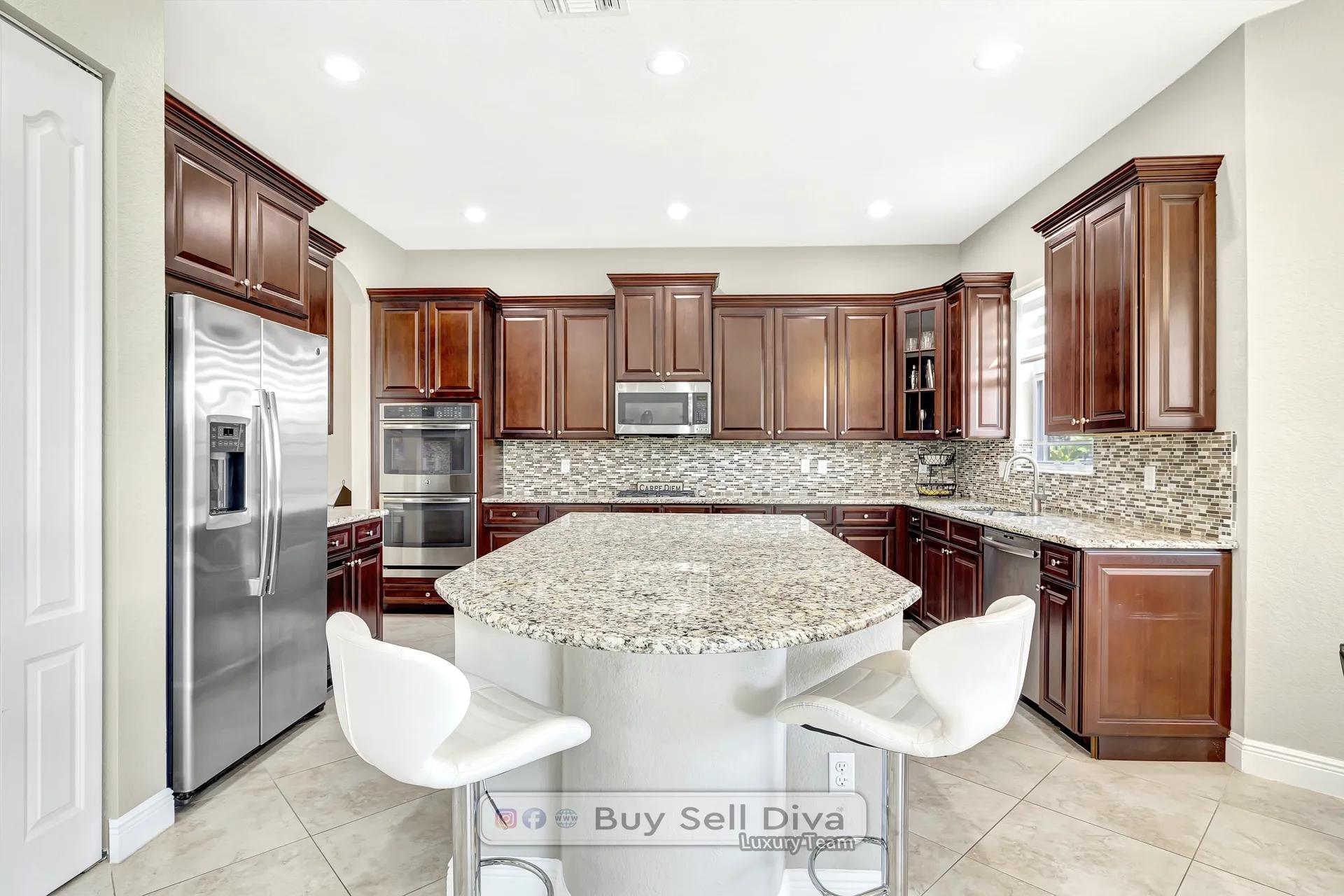 Upgraded kitchen with granite island, wood cabinets, and double wall ovens inside the MiraLago home in Parkland Florida