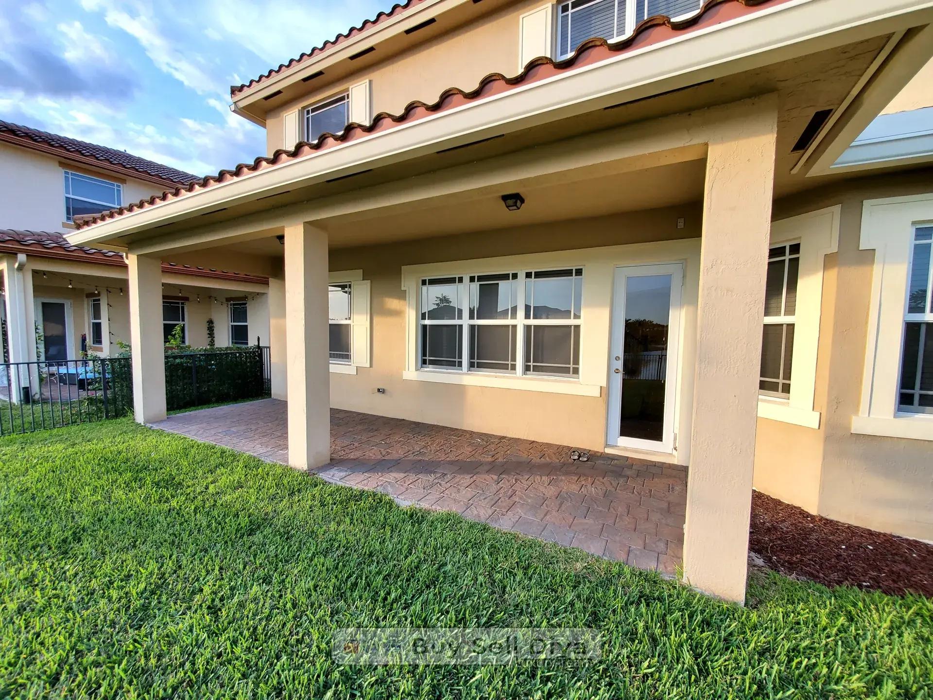 Covered backyard patio with paver flooring and waterway view at 10260 Lake Vista Court in Parkland Florida
