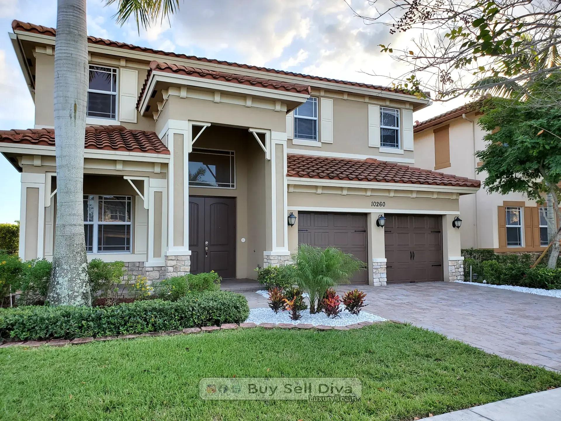 Covered front entry with double doors and stone accents at the MiraLago home in Parkland Florida