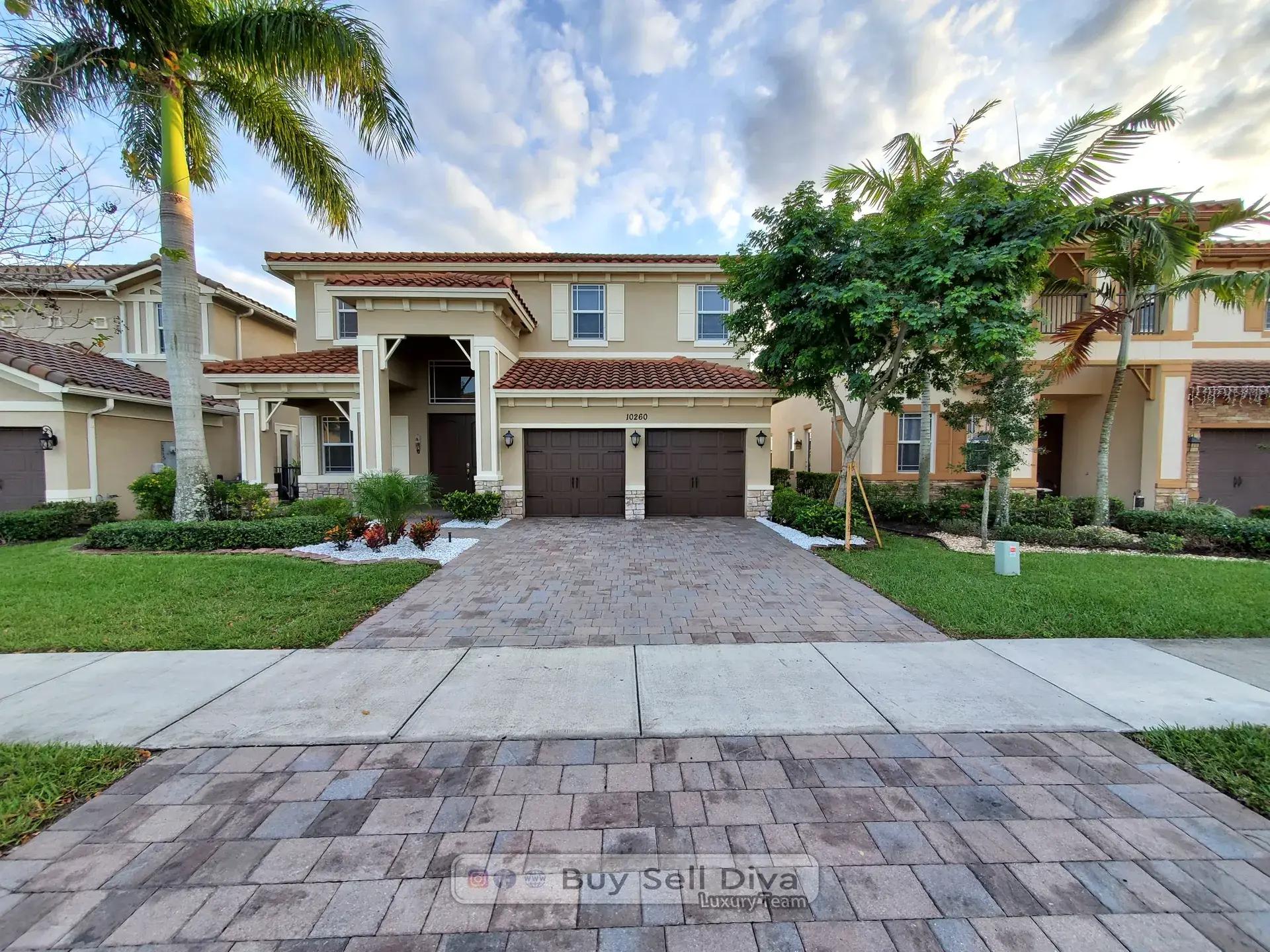 Front exterior of 10260 Lake Vista Court in MiraLago Parkland Florida with paver driveway and two garage doors
