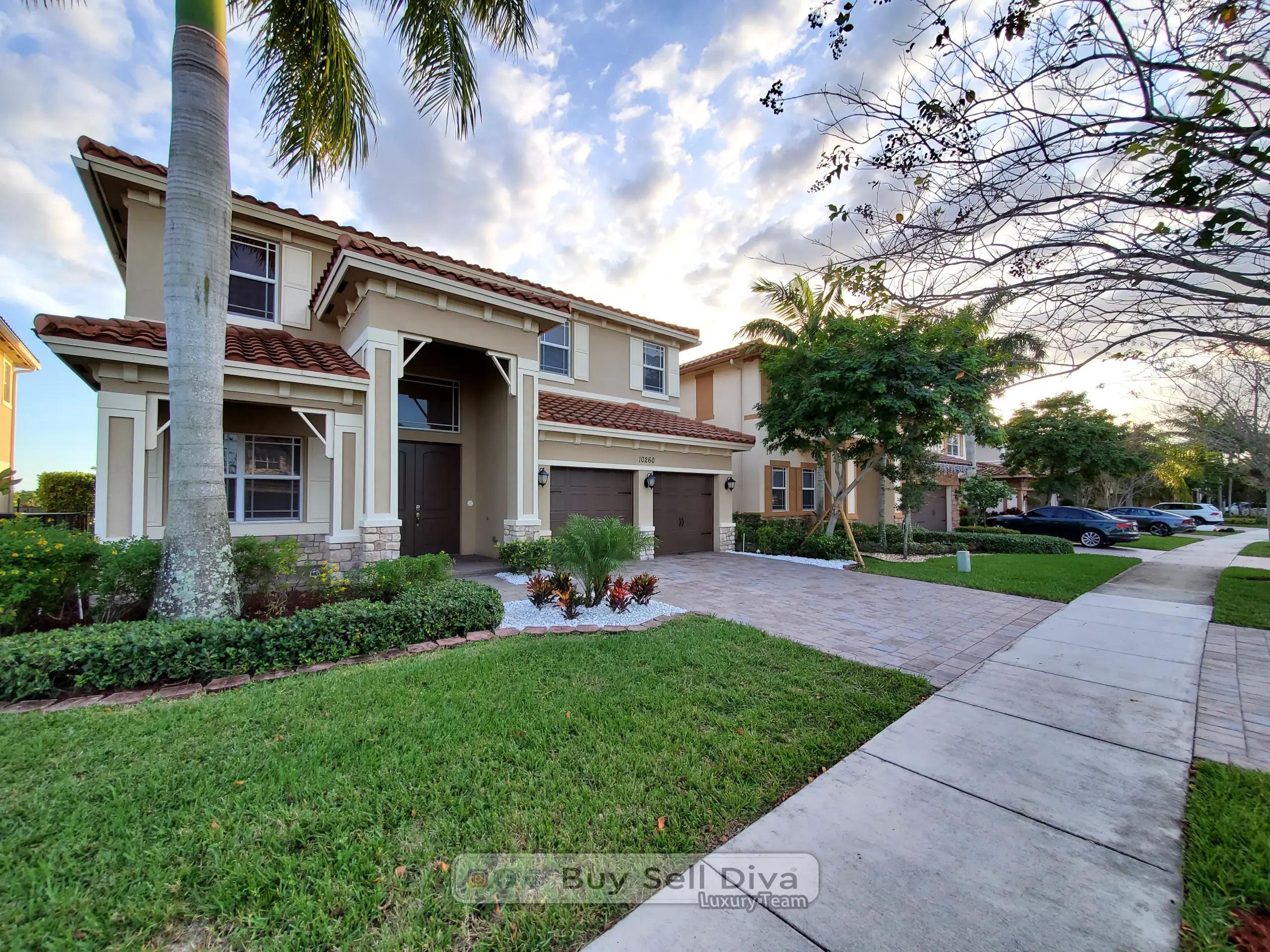 Two-story home at 10260 Lake Vista Court in MiraLago Parkland Florida at sunset with royal palm, paver driveway, and barrel tile roof