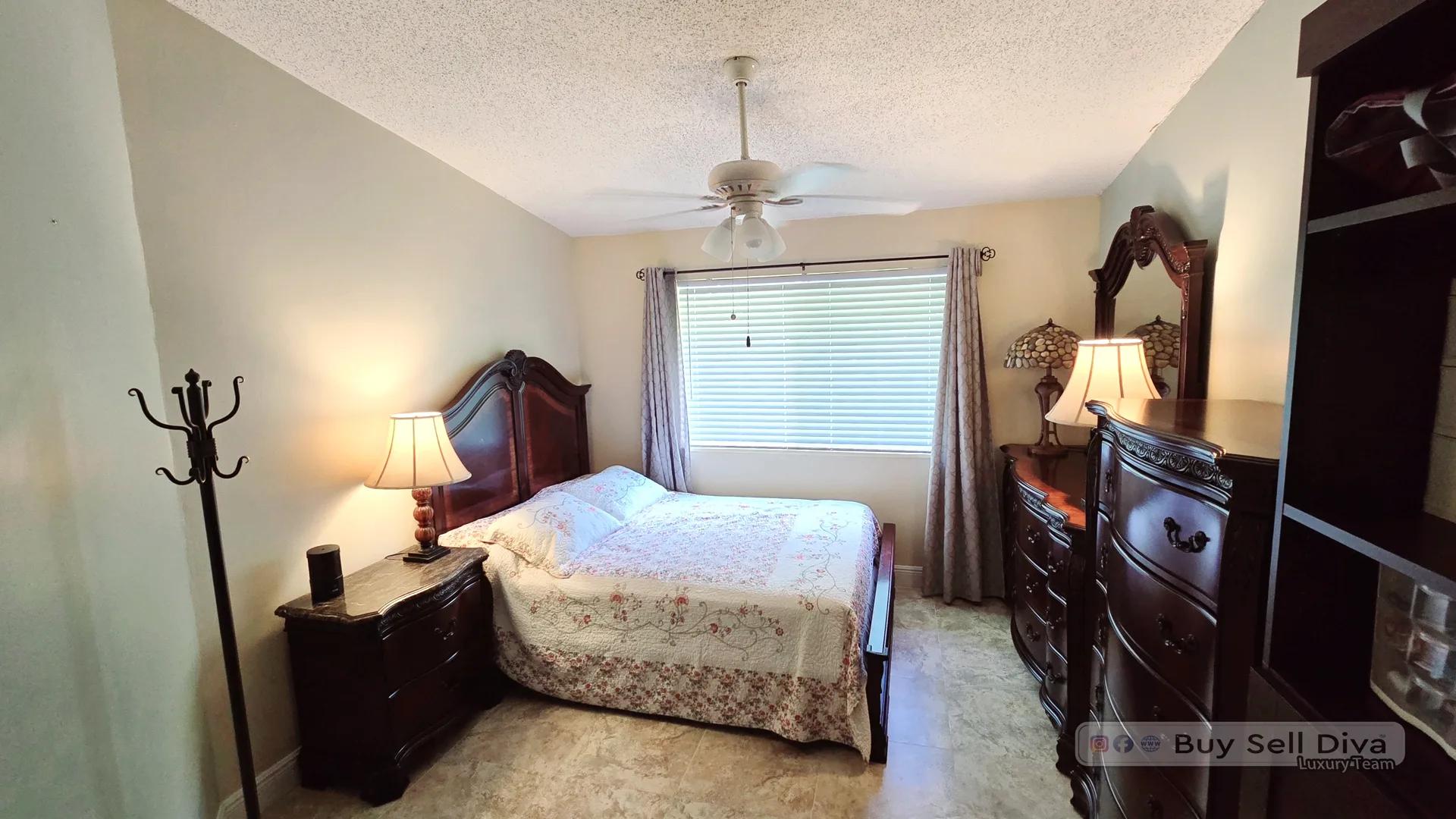 Primary bedroom with carpet and a bright window in a Villager Townhomes townhouse for rent in Deerfield Beach