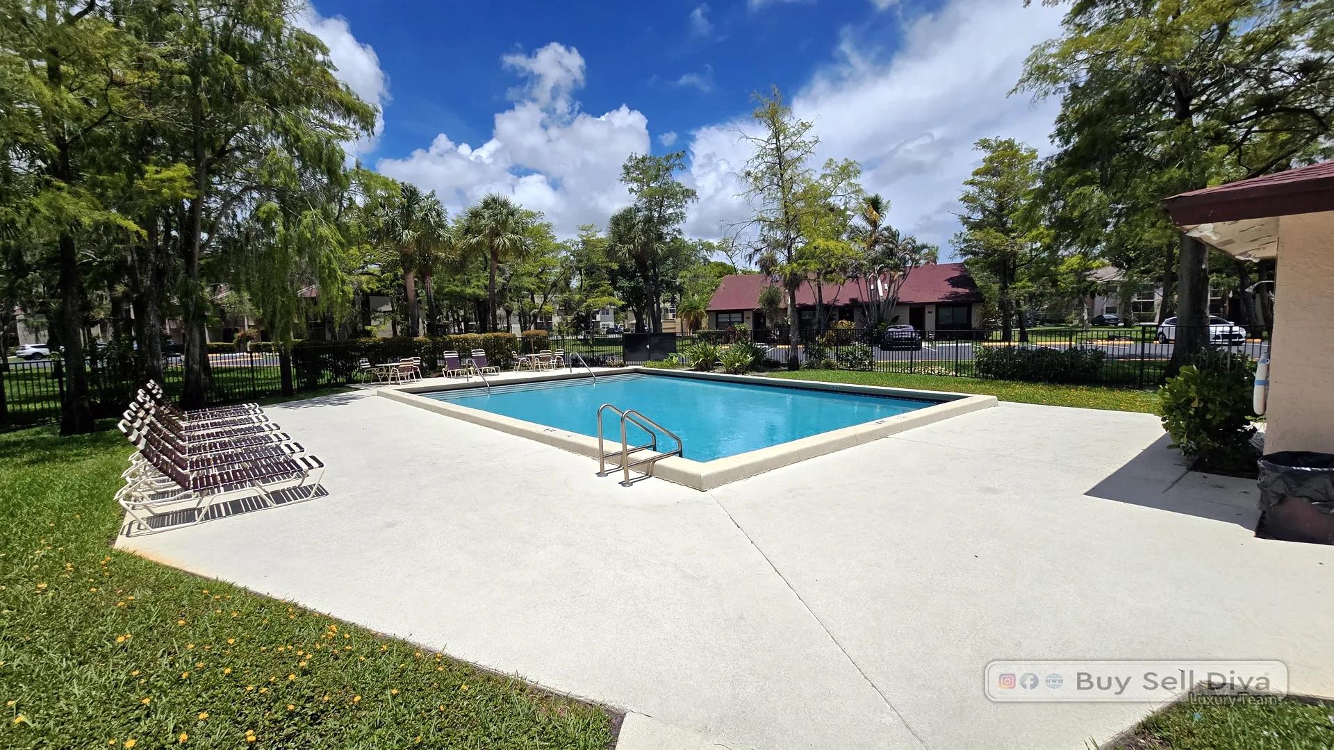 Community swimming pool with a sundeck at Villager Townhomes, a Deerfield Beach rental community in Broward County