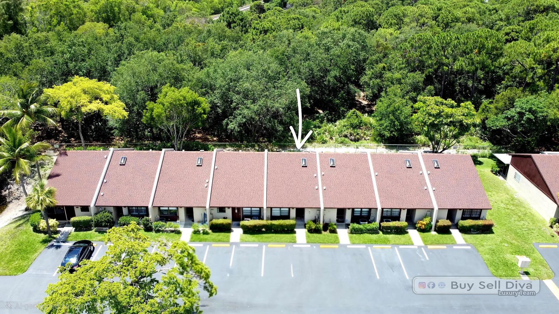 Aerial view of Villager Townhomes in Deerfield Beach, a Broward County rental community of red-roof townhouses backing to a wooded preserve