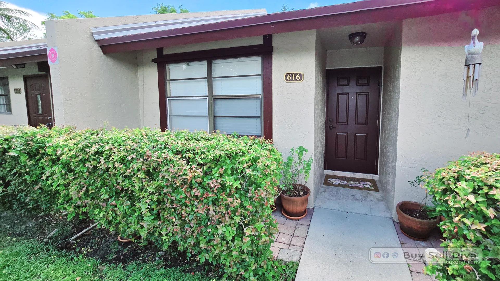 Private front entry of a Villager Townhomes townhouse for rent in Deerfield Beach with a landscaped walkway
