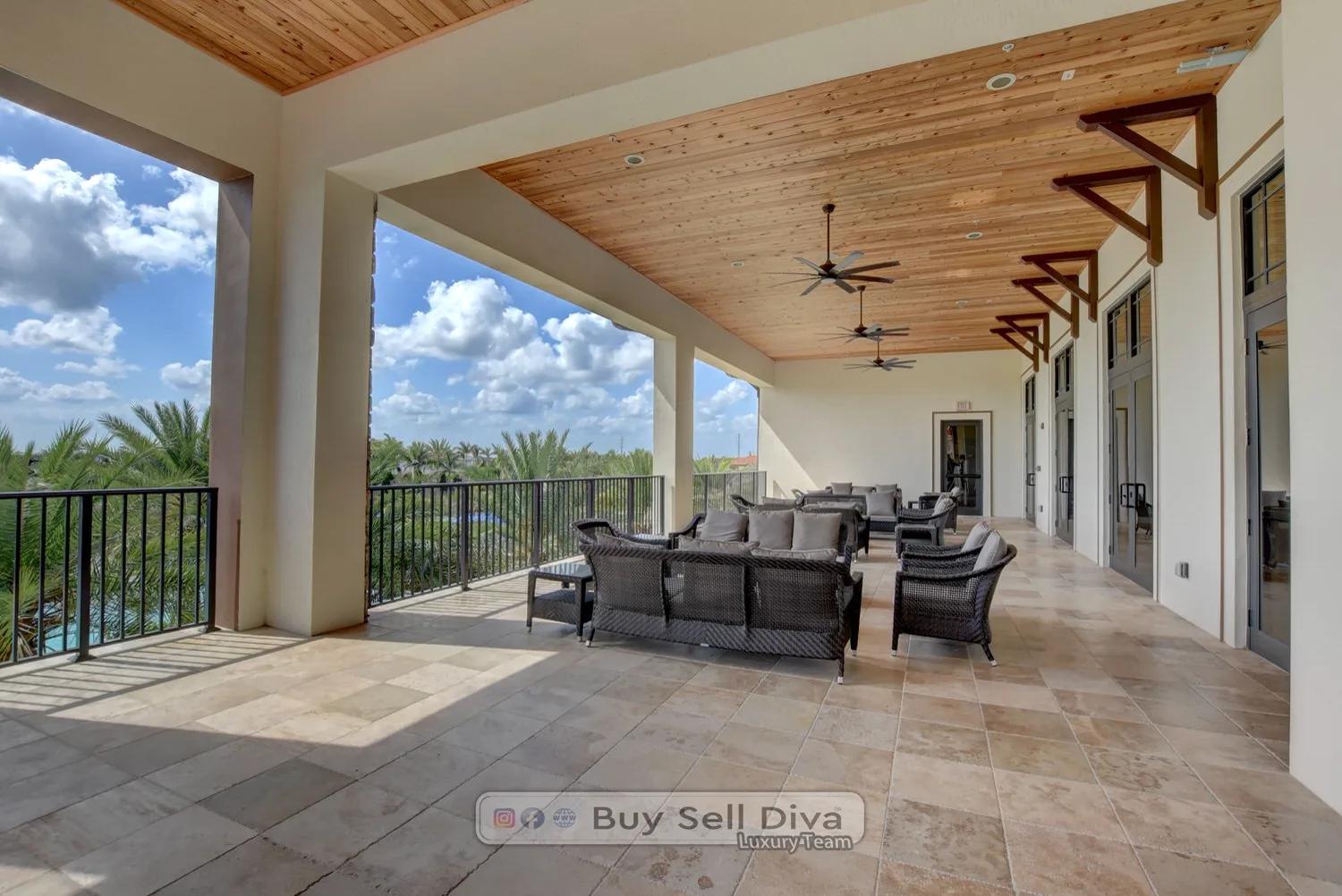 Second-floor covered terrace with lounge seating overlooking palms at the MiraLago clubhouse in Parkland Florida