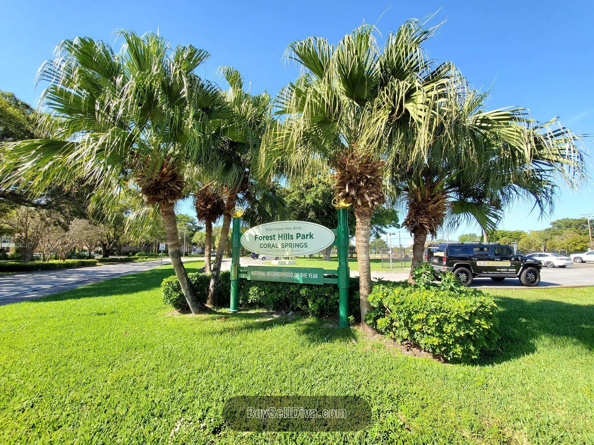 Entry sign at Forest Hills Park in Coral Springs, FL: green oval neighborhood-park sign framed by palm trees and landscaped beds