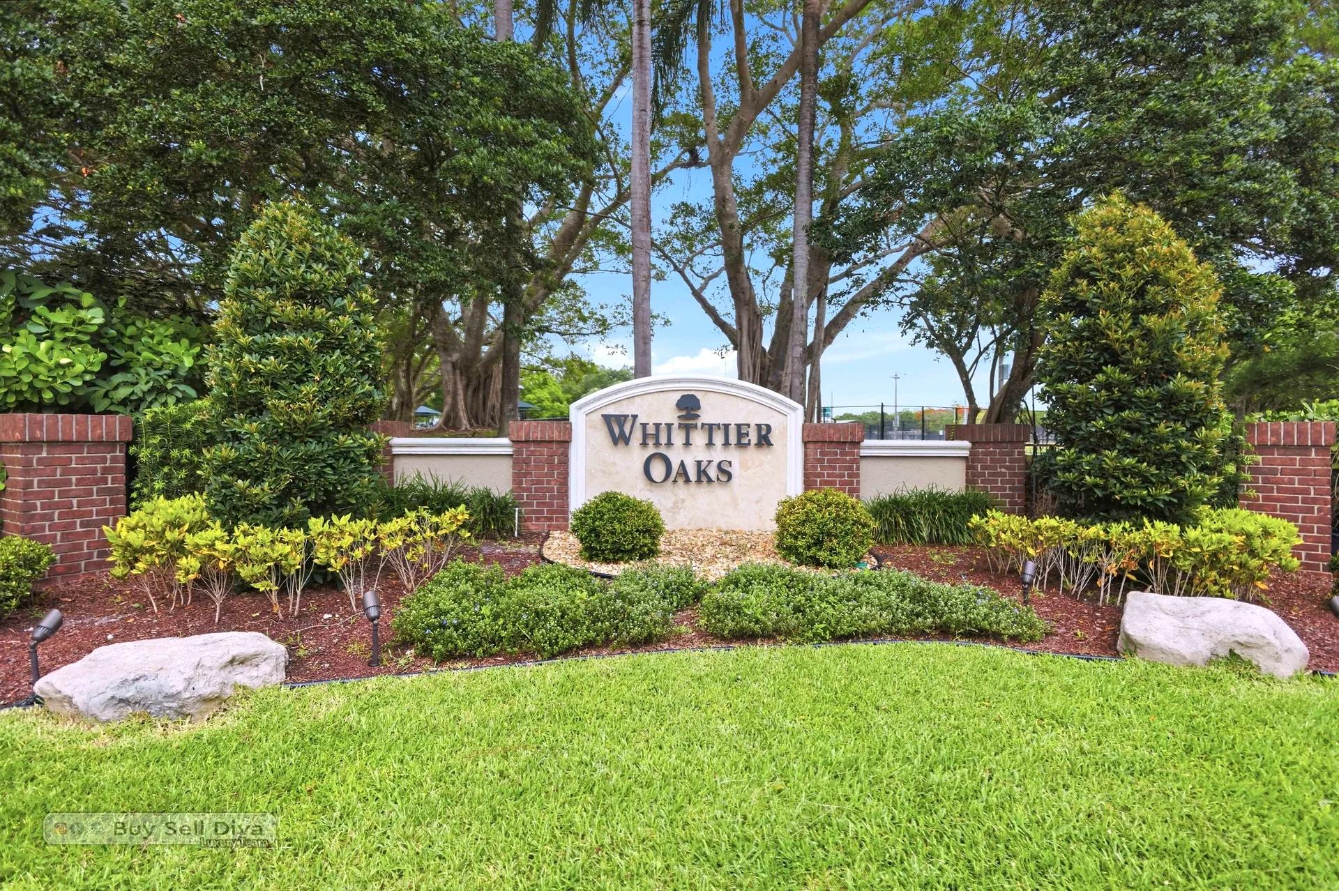 Whittier Oaks community entrance sign surrounded by oaks and landscaped beds in Parkland Florida